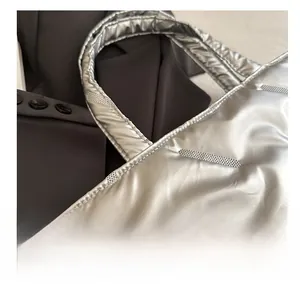 Detail view of silver quilted tote bag with metallic sheen and decorative stitching