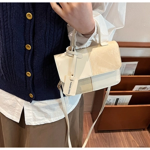 Detail of a beige two-tone rectangular handbag with matte leather and suede textures