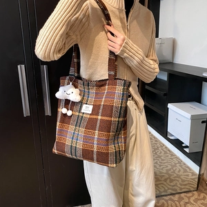 Retro plaid wool tote bag with cloud pendant shown on shoulder in cozy interior