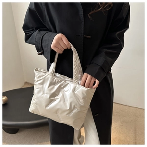Detailed view of silver quilted tote bag featuring metallic finish and soft padded handles