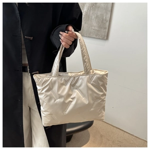 Close-up of a quilted beige puffer tote bag featuring modern padded texture and top handles