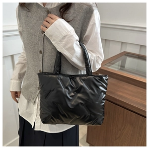 Detail of black quilted tote bag with padded texture and stitching for daily commute