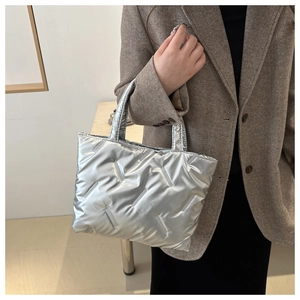 Close-up of quilted silver puffer tote bag with metallic finish and padded top handles