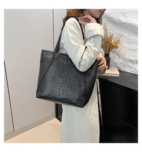 Detailed view of women's black crocodile pattern leather tote bag with long shoulder straps