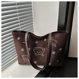 Detail of brown suede tote bag with white bear embroidery and leather shoulder strap