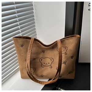 Detailed close-up of brown suede tote bag with cute cartoon bear embroidery and straps