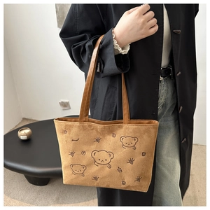 Detail of brown suede tote bag with cartoon bear embroidery and leather straps
