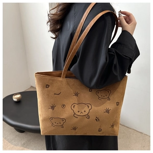 Brown suede tote bag detail featuring cartoon patterns and long shoulder straps for daily use