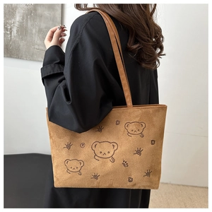 Brown suede tote bag with embroidered cute bear design shown on model's shoulder