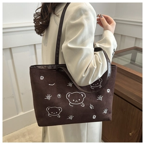 Detail of dark brown tote bag featuring white embroidered cartoon bears and stars