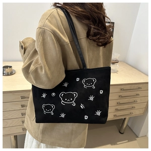 Detail of a large black canvas tote bag featuring cute cartoon bear and star prints