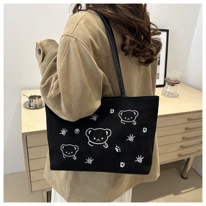 Close-up of black tote bag featuring a cute white embroidered cartoon bear design