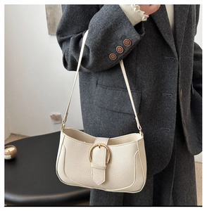 Detailaufnahme der cremefarbenen Baguette-Tasche mit Litschistruktur und Gold-Schnalle