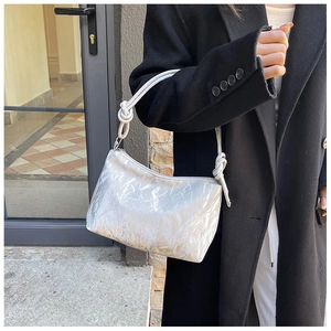 Detailed view of silver pleated texture and knotted strap on stylish underarm bag