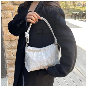 Close-up of white knotted strap shoulder bag with textured glossy fabric and hobo design