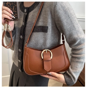 Detailaufnahme der braunen Tasche mit Litschi-Muster und goldener Hufeisenschnalle