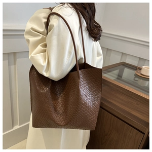 Brown woven tote bag side view on model highlighting the premium leather texture