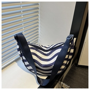 Detail of blue and white striped nylon crescent bag with wide navy adjustable strap