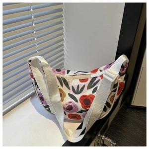 Close-up of a floral print half-moon crossbody bag with wide adjustable woven strap