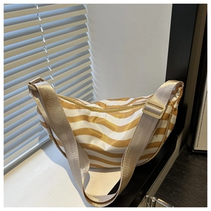Detail of striped yellow crossbody bag with adjustable strap in natural lighting