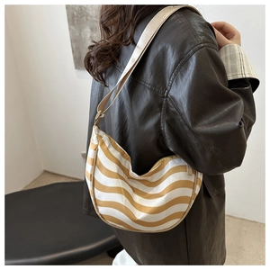 Detail view of yellow wave pattern crescent bag worn as a shoulder bag on model