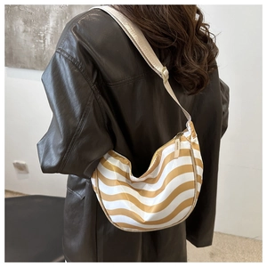 Detail of yellow and white wave pattern nylon crescent bag worn over a brown leather coat