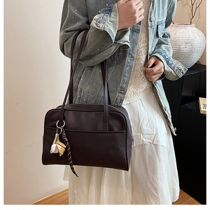 Detail view of large coffee brown tote bag with baseball pendant and ribbon accessory