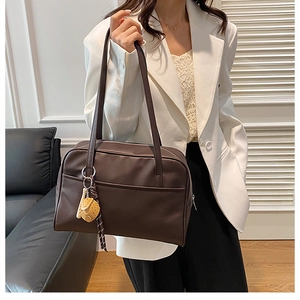 Deep brown matte leather tote bag with long straps and a cute cartoon animal charm