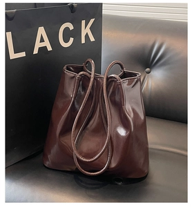 Close-up of glossy coffee-colored tote bag on leather sofa with soft wrinkled texture