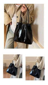 Detail of glossy black tote bag made of high-shine patent leather with slim shoulder straps