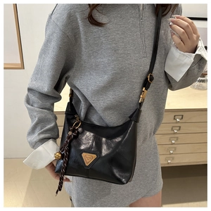 Détail du sac bandoulière en cuir noir avec ferrures dorées et pendentif clochette