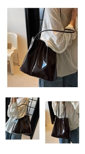 Macro detail of dark brown glossy leather tote bag showing fine texture and sleek finish