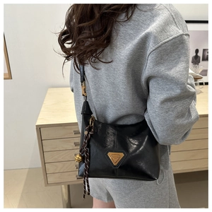 Détail du sac à bandoulière noir en similicuir brillant avec un charmant grelot doré