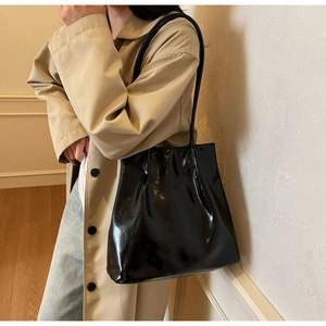Macro detail of high-gloss black leather tote bag with elegant minimalist shoulder strap