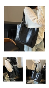 Close-up of a large black waxed faux leather tote bag with glossy crackle texture