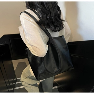 Large black oil wax leather tote bag shown on shoulder for daily commute style