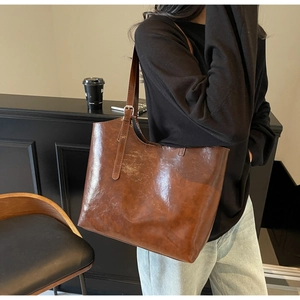 Detailed view of brown oil wax leather tote bag with adjustable silver metal buckle strap
