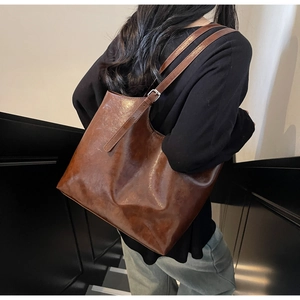 Detail of dark brown oil wax leather tote bag with glossy texture and slim shoulder strap