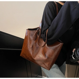 Close-up of a large vintage brown oil wax leather tote bag worn as a shoulder bag