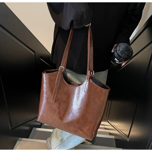 Brown oil-waxed leather tote bag showing large capacity and adjustable straps on stairs