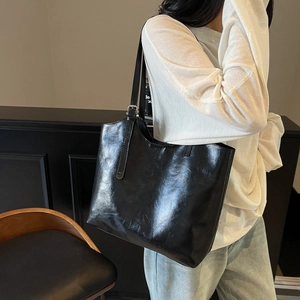 Large black oil wax leather tote bag with silver buckle worn by a model for daily commute