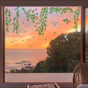 Green vine window clings with birds and pink flowers over sunset scenery
