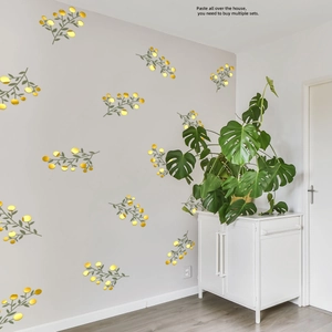 Detail of gold circular mirror decals with green leaves on grey wall in living room decor