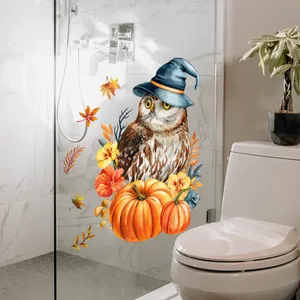 Detail of owl and pumpkin window cling applied to a glass shower door with autumn leaves