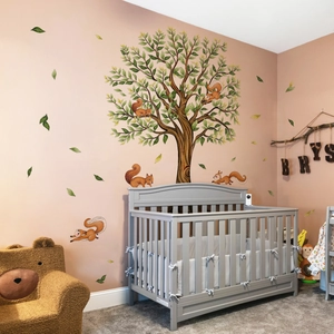 Detail of tree wall sticker with squirrels and green leaves in a cozy nursery room setting