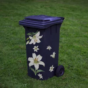 Detail of outdoor wheelie bin with white lily floral pattern on purple surface