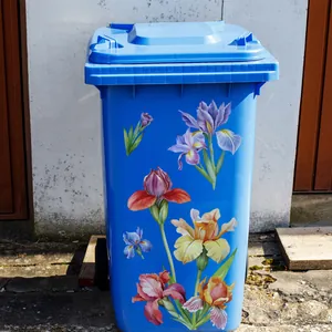 Close-up of blue outdoor trash bin featuring colorful iris floral self-adhesive decals
