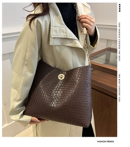 Détail de la texture damier tressé marron foncé avec fermoir rotatif en métal doré sur sac