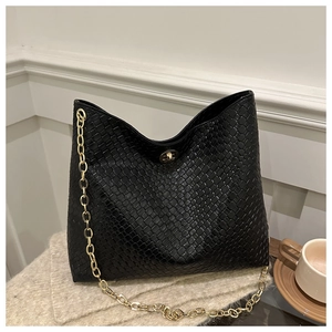 Détail du sac fourre-tout tissé noir avec une grosse chaîne dorée et fermoir rotatif