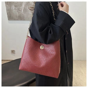 Détail du sac rouge à texture tressée avec chaîne dorée et fermoir rotatif